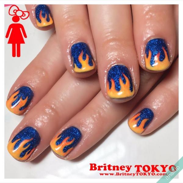 [BritneyTOKYO/カラフル/個性派/アメリカン/ポップ/ショート/オーバル/ブルー/青/ラメ/オレンジ/イエロー/黄色/炎/ファイアー]のタグが付いたネイルデザイン